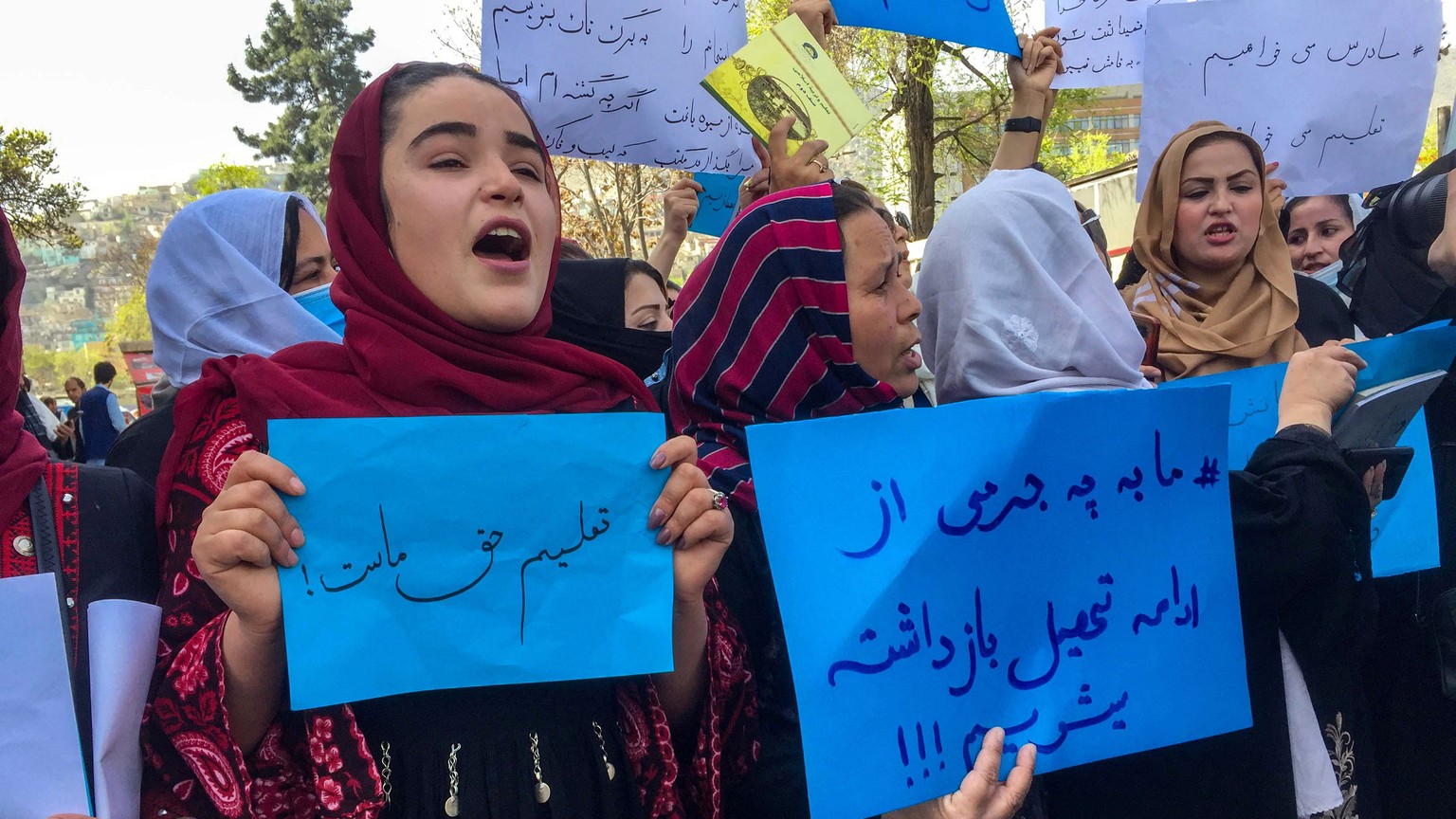 epa09850646 Afghan teachers hold placads during a protest near the main entrance of the ministry of education for raising their voices for their education rights and reopening the secondary and high s ...