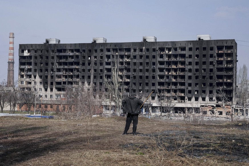 A man looks at a burned apartment building that was damaged by shelling in Mariupol, Ukraine, Sunday, March 13, 2022. (AP Photo/Evgeniy Maloletka)