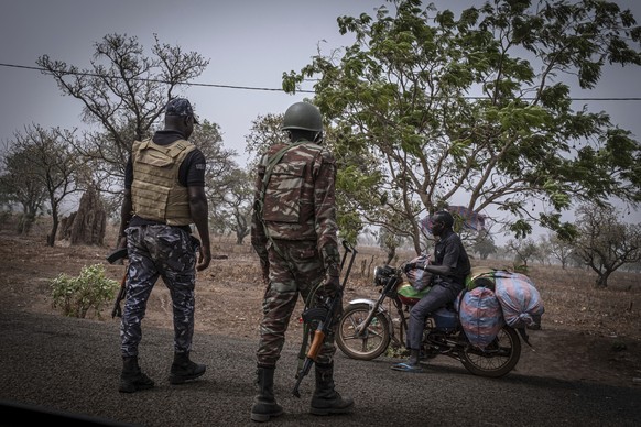 A police officer and a soldier from Benin stop a motorcyclist at a checkpoint outside Porga, Benin, March 26, 2022. Porga, in the Atakora region of northern Benin bordering Burkina Faso, has suffered  ...