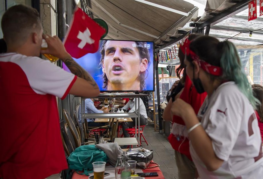 Swiss football fans react as the goalkeeper of the Swiss team Yann Sommer appears on the screen, during the live broadcast of the UEFA Euro 2020 Quarter-finals football match between Switzerland and S ...