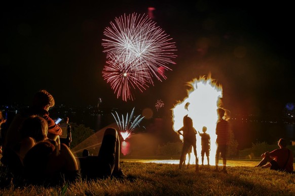 Les spectateurs regardent le feu de joie traditionnel avec un feu d'artifice, lors de la fête nationale suisse, à Cologny près de Genève, en Suisse, le mardi 1er août 2017.