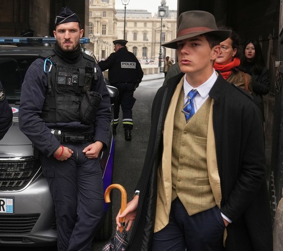 L&#039;homme, vêtu d&#039;un gilet boutonné, d&#039;un trench-coat et d&#039;un fedora, qui semblait surveiller la scène, a déclenché l&#039;indignation sur Internet. (AP Photo/Thibault Camus)