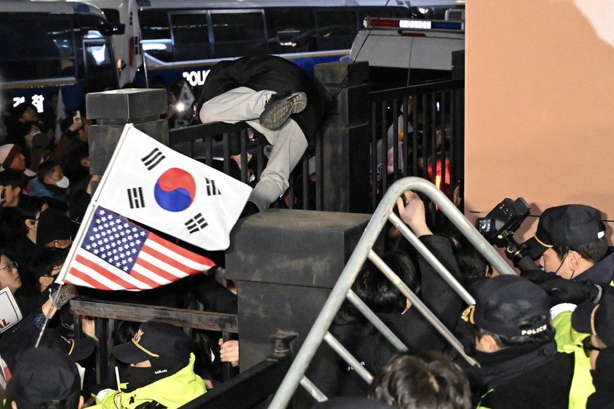 epa11835292 A supporter of suspended President Yoon Suk Yeol climbs over a wall to enter the Seoul Western District Court after Yoon was formally arrested in Seoul, South Korea, 19 January 2025. EPA/Y ...