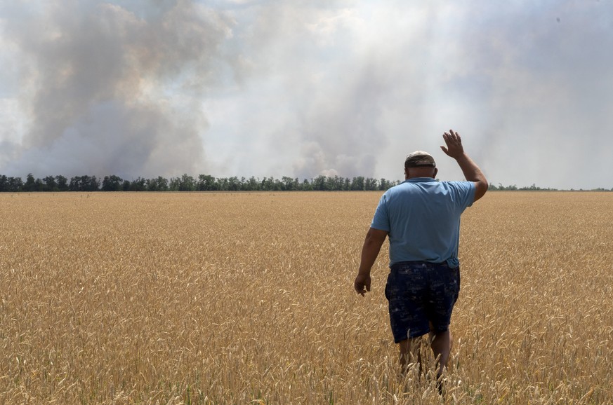 FILE - A farmer reacts as he looks at his burning field caused by the fighting at the front line in the Dnipropetrovsk region, Ukraine, Monday, July 4, 2022. Military officials from Russia and Ukraine ...