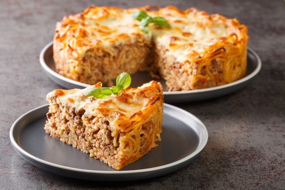 Cheesy Baked Spaghetti Pie with Ground beef, spicy and tomato sauce closeup in the plate on the table. Horizontal