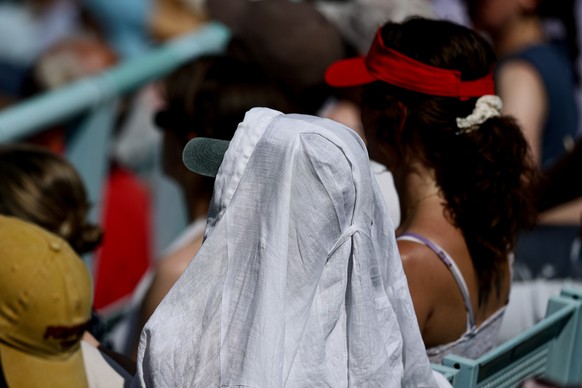 epa13048923 A spectator covers the head against the sun during a hot day at the WTA 500 Berlin Open tennis tournament at Steffi Graf Stadium in Berlin, Germany, 19 June 2026. EPA/FILIP SINGER