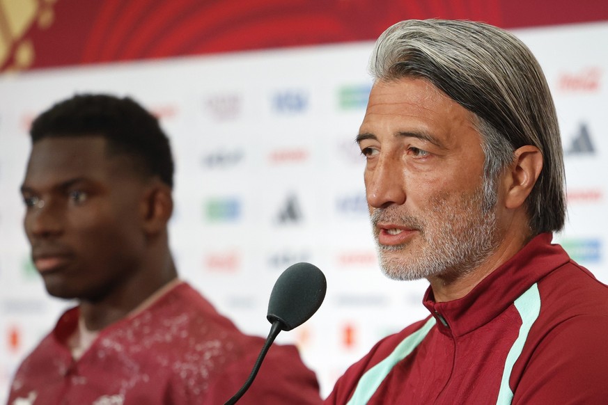 epa13079011 Switzerland head coach Murat Yakin (R) speaks beside player Breel Embolo (L) during a press conference one day ahead of the FIFA World Cup round of 32 soccer match between Switzerland and  ...