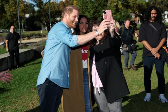 epa12892869 Prince Harry (L) and Meghan (C), the Duke and Duchess of Sussex, take a selfie with a person during the Scar Tree Walk at Birrarung Marr in Melbourne, Australia, 16 April 2026. The Duke an ...