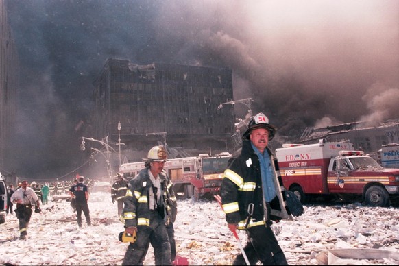 Des pompiers de la ville de New York marchent près de la zone connue sous le nom de Ground Zero après l&#039;effondrement des tours jumelles le 11 septembre 2001 à New York.