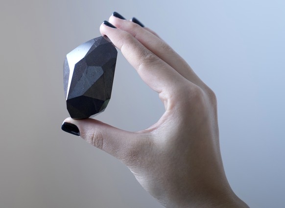 An employee of Sotheby&#039;s Dubai presents a 555.55 Carat Black Diamond &quot;The Enigma&quot; to be auctioned at Sotheby&#039;s Dubai gallery, in Dubai, United Arab Emirates, Monday, Jan. 17, 2022. ...