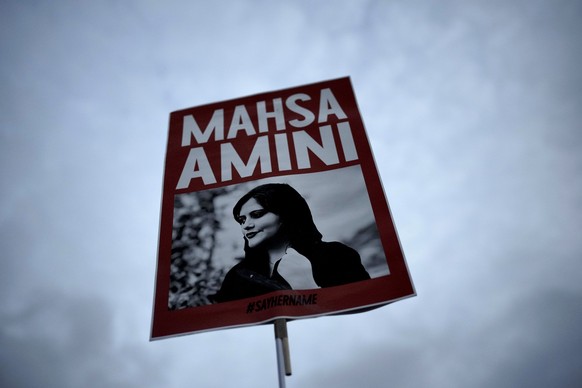 FILE - A woman holds a placard with a picture of Iranian woman Mahsa Amini during a protest against her death, in Berlin, Germany, Wednesday, Sept. 28, 2022. Mahsa Amini, the 22-year-old Kurdish-Irani ...