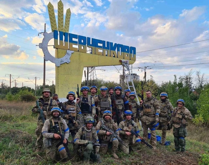 Des soldats ukrainiens posent devant un panneau dans le village de Shevchenkove, fraîchement libéré.