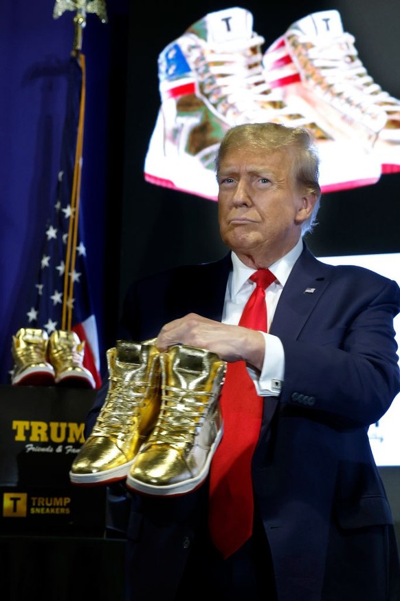 PHILADELPHIA, PENNSYLVANIA - FEBRUARY 17: Republican presidential candidate and former President Donald Trump holds a pair of his new line of signature shoes after taking the stage at Sneaker Con at t ...