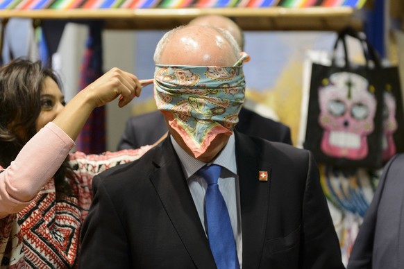 Une dame du stand du Mexique pose un foulard sur les yeux de Ueli Maurer, centre, Conseiller federal, pendant une visite du stand du Mexique a l&#039;occasion de l&#039;ouverture du Comptoir Suisse ce ...