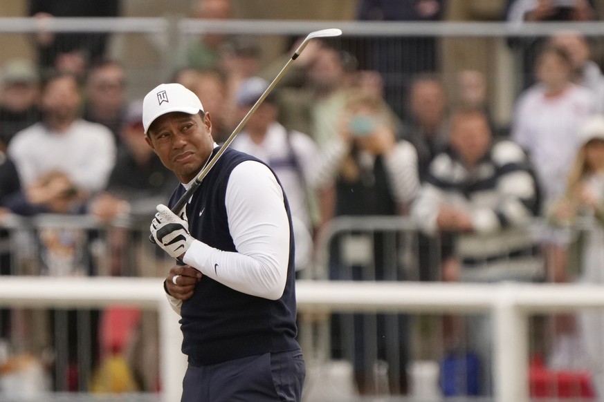 Tiger Woods of the US reacts to dust after playing a shot on the 1st hole during the first round of the British Open golf championship on the Old Course at St. Andrews, Scotland, Thursday, July 14 202 ...