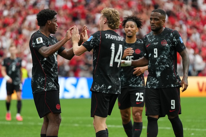 Canada's Jonathan David, left, celebrates with teammates after scoring his side's sixth goal for a hat trick during the World Cup Group B soccer match against Qatar in Vancouver, British Col ...