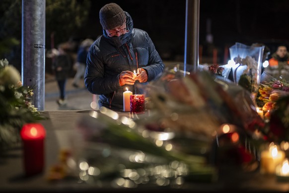 epa12621017 A man lights a candle to remember the victims of the fire at the "Le Constellation" bar and lounge leaving people dead and injured, during New Year?s celebration, in Crans-Montan ...
