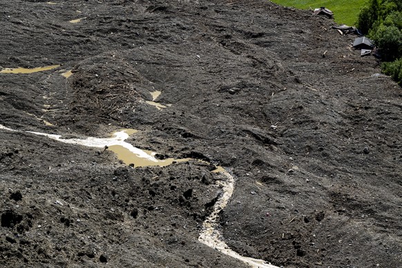 KEYPIX - Water from the Lonza river flows over the mud and stone, after the formation of a lake on the last houses of the village of Blatten, Switzerland, Friday, May 30, 2025. A large part of the vil ...