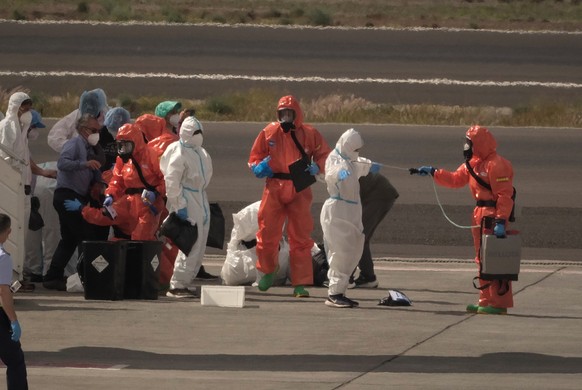 Passengers are sprayed with disinfectant by Spanish government officials before boarding a plane after disembarking from the hantavirus-stricken cruise ship MV Hondius at Tenerife airport in the Canar ...