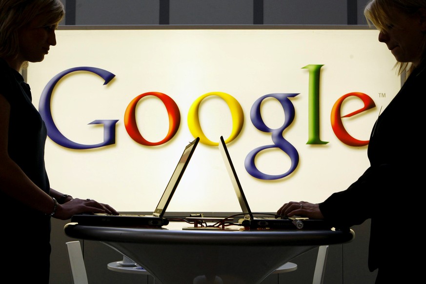 FILE - In this April 17, 2007 file photo, exhibitors work on laptop computers in front of an illuminated sign of the Google logo at the industrial fair Hannover Messe in Hanover, Germany. German regul ...