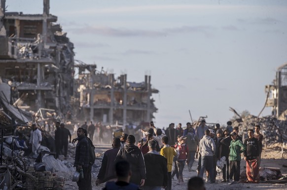 epa11840330 Internally displaced Palestinians walk along a street among the rubble of destroyed buildings amid a ceasefire between Israel and Hamas, in Rafah, southern Gaza Strip, 20 January 2025. Isr ...