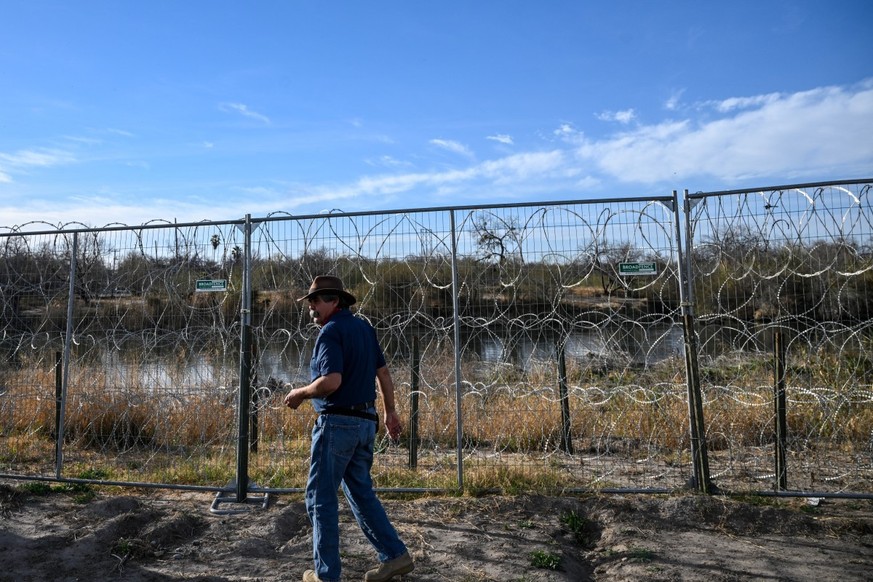 Jessie Fuentes, who owns a kayaking company in Eagle Pass, walks along a fence at the Rio Grande river that marks the US-Mexico border at Shelby Park in Eagle Pass, Texas, on February 18, 2026. (Photo ...