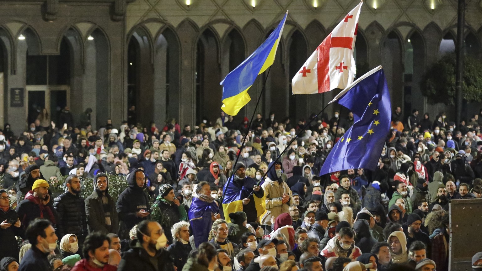 Protesters wave Ukrainian, Georgian and EU flags as they gather outside the Georgian parliament building in Tbilisi, Georgia, Wednesday, March 8, 2023. Georgian authorities used tear gas and water can ...
