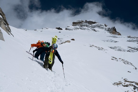 Jérémie Heitz et Sam Anthamatten en train de gravir une montagne skis sur l'épaule.