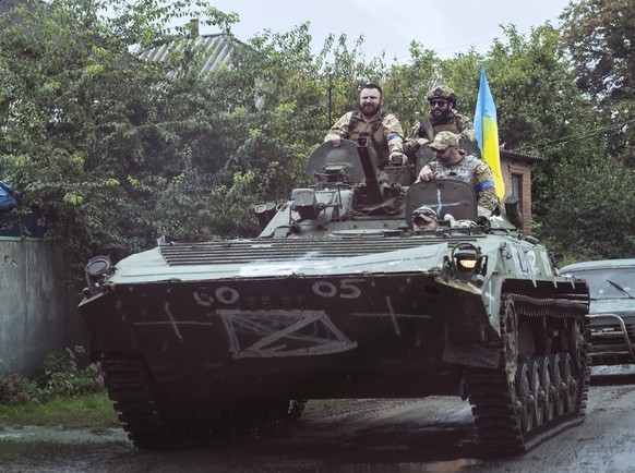 epa10188667 Ukrainian servicemen ride an armoured personnel carrier (APC) with a national flag at a street in the recently recaptured city of Izyum, Kharkiv region, northeastern Ukraine, 16 September  ...