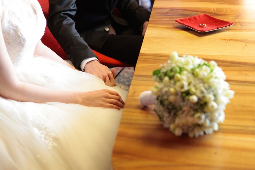 a picture of bride and groom holding hands and the wedding bouquet of freesia