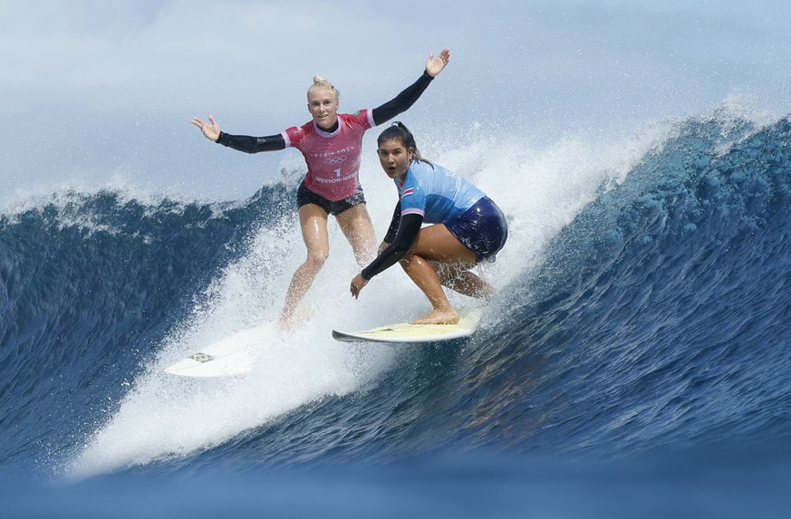 Tatiana Weston-Webb, of Brazil, left, reacts as Brisa Hennessy, of Costa Rica, drops in on her during the semifinal round of the surfing competition at the 2024 Summer Olympics, Monday, Aug. 5, 2024,  ...