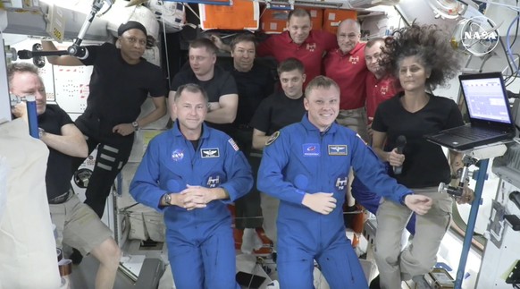 In this image made from a NASA livestream, the two astronauts stuck at the International Space Station since June 2024, Butch Wilmore, far left, and Suni Williams, far right, welcome two new residents ...