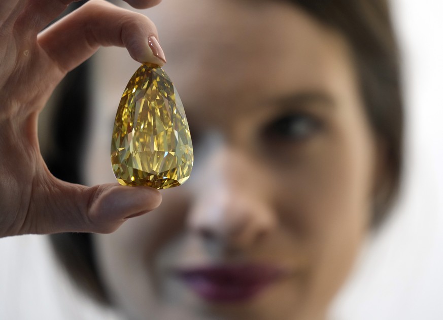 Sotheby&#039;s jewellery specialist Sophie Stevens holds a Golden Canary polished diamond displayed at the Sotheby&#039;s Dubai gallery, Monday, Oct. 17, 2022, in Dubai, United Arab Emirates. The larg ...