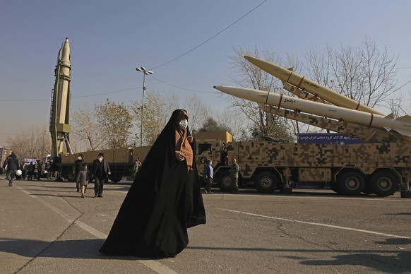 ADDS NAMES OF MISSILES - A woman walks past Qiam, left, Zolfaghar, top right, and Dezful missiles displayed in a missile capabilities exhibition by the paramilitary Revolutionary Guard a day prior to  ...