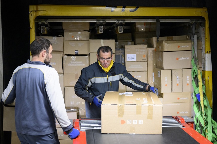 Des employes de la poste suisse chargent des paquets &quot;Zalando&quot; dans un container au centre colis de La Poste ce jeudi 15 decembre 2022 a Daillens, Vaud. Pendant les jours de pointe avant Noe ...