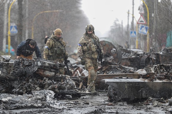 Des soldats ukrainiens dans les rues de Boutcha, jonchées de véhicules russes détruits.