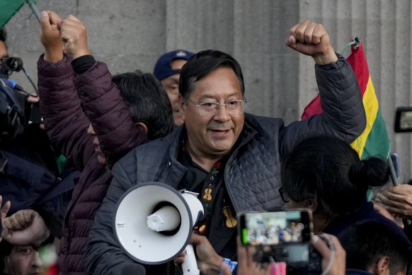 Bolivian President Luis Arce raises a clenched fist surrounded by supporters and media, outside the government palace in La Paz, Bolivia, Wednesday, June 26, 2024. Armored vehicles rammed the doors of ...
