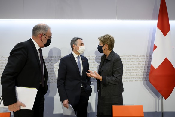 Bundespraesident Ignazio Cassis, Mitte, Bundesrat Guy Parmelin, links, und Bundesraetin Karin Keller-Sutter, rechts, sprechen nach einer Medienkonferenz zu den Beschluessen des Bundesrats um Thema Ukr ...