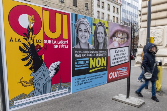 Une personne passe devant des affiches sur la votation cantonale et sur la loi sur la laicite de l'Etat et le remboursement des soins dentaires, ce dimanche 20 janvier 2019 a Geneve. Les citoyens ...