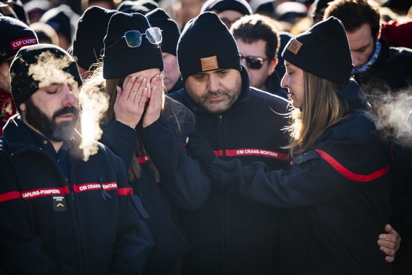 epa12625415 Firefighters of Crans-Montana, first responders in the fire at the "Le Constellation" bar and lounge, show emotions as they gather around flowers and candles to commemorate the v ...