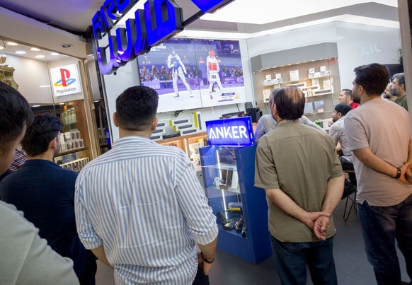 Iranian men are watching a taekwondo match at the 2024 Paris Olympics, between Nahid Kiani from Iran and Kimia Alizadeh, who is also Iranian but represents Bulgaria, at a computer shop in Tehran, Iran ...