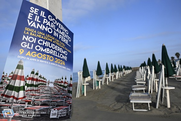 epa11538866 A poster calling for a strike is seen beside deck chairs and umbrellas closed during a two-hour strike by beach operators at the Belsito beach in the seaside resort of Ostia, outside Rome, ...