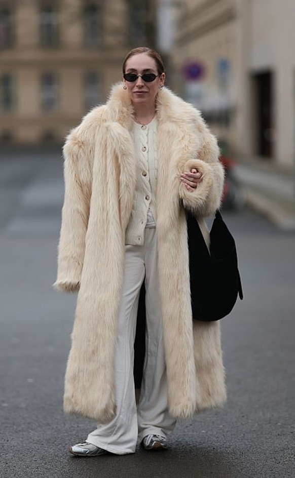 BERLIN, GERMANY - DECEMBER 10: Sonia Lyson is seen wearing black, oval-shaped Vehla sunglasses. Her outfit is cream-colored, consisting of a long, oversized faux fur coat that reaches her ankles. Unde ...