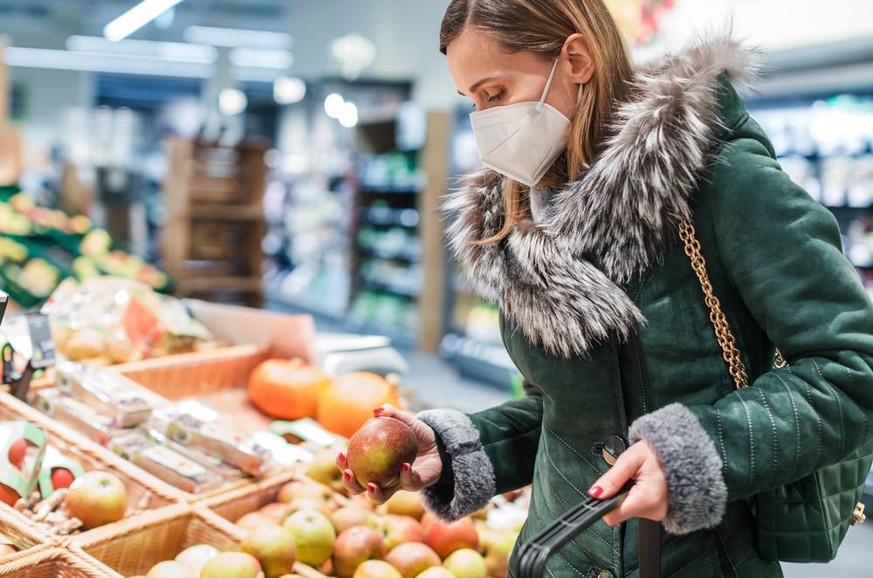 Frau mit FFP2-Maske kauft ein.