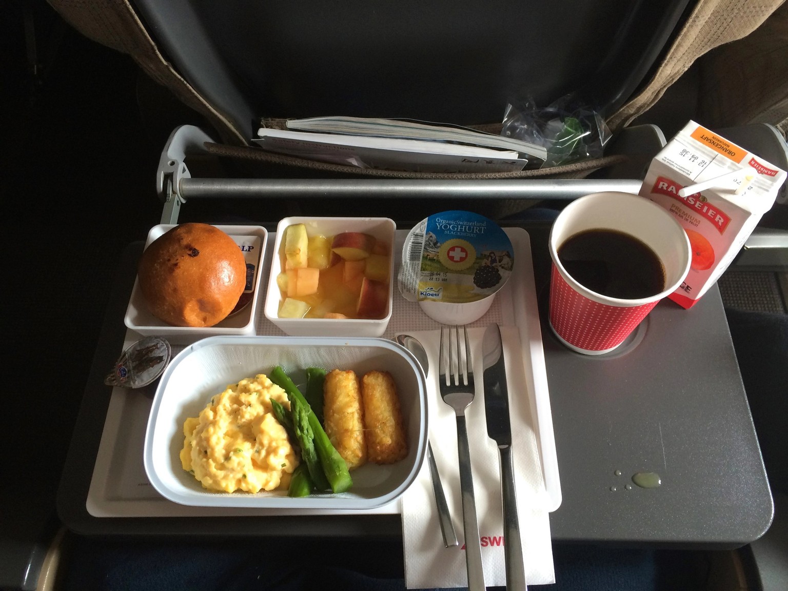ZURICH, SWITZERLAND - MAR 31st, 2015: A breakfast meal with coffee, butter, bread, yogurt and scrambled eggs on a tray, onboard a longhaul flight to Singapore in economy class.