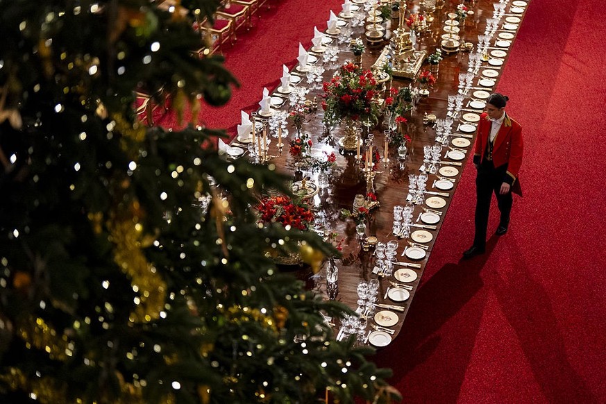 WINDSOR, ENGLAND - DECEMBER 03: A member of Royal Household staff arranges table placements ahead of the state banquet for the German President Frank-Walter Steinmeier and his wife Elke Budenbender, o ...