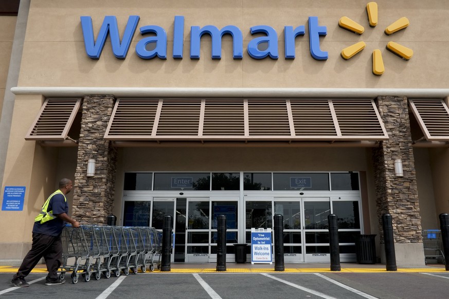 FILE - In this May 9, 2013, file photo, a worker pushes shopping carts in front of a Wal-Mart store in La Habra, Calif. Retail giant Walmart illegally dumps more 1 million batteries, aerosol cans of i ...