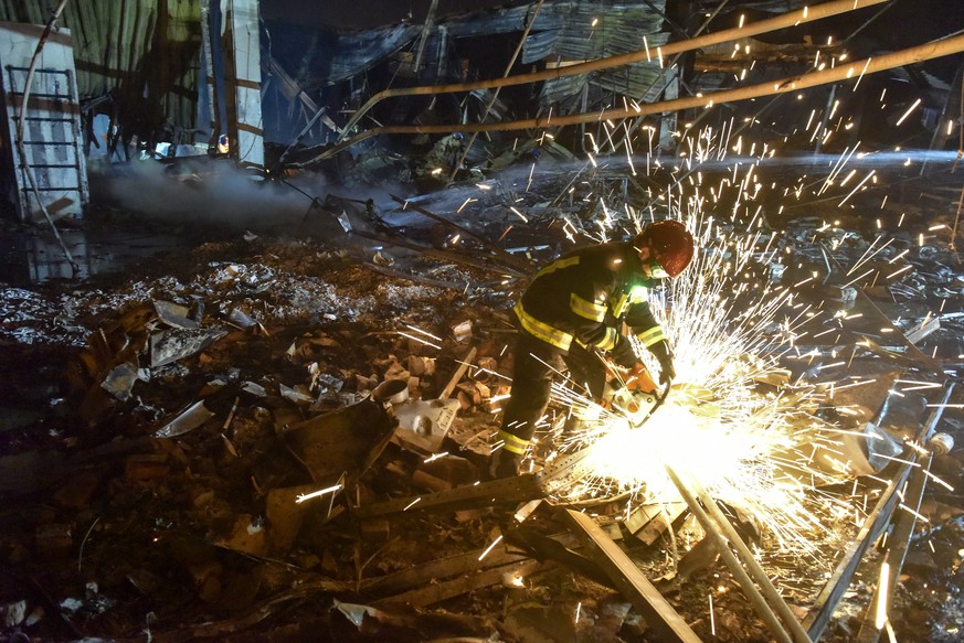 epa10037555 Firefighters and rescue workers clean the rubble of destroyed Amstor shopping mall in Kremenchuk, Poltava Oblast, Ukraine, 27 June 2022. At least eleven bodies were found dead at the scene ...