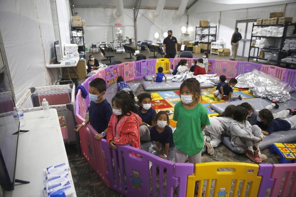 FILE - In this March 30, 2021 file photo Young unaccompanied migrants, from ages 3 to 9, watch television inside a playpen at the U.S. Customs and Border Protection facility, the main detention center ...