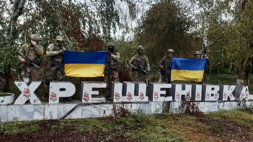 Soldats ukrainiens devant le panneau de la ville de Khrechtchenivka.